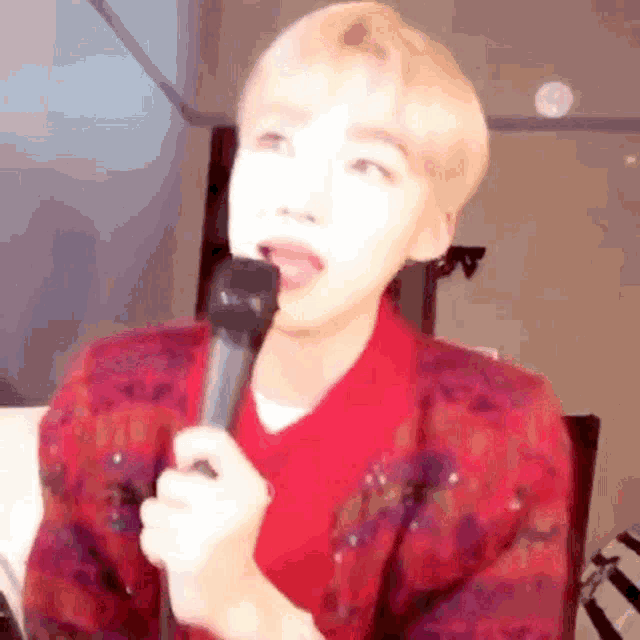 a young man is holding a microphone in his mouth and making a funny face .