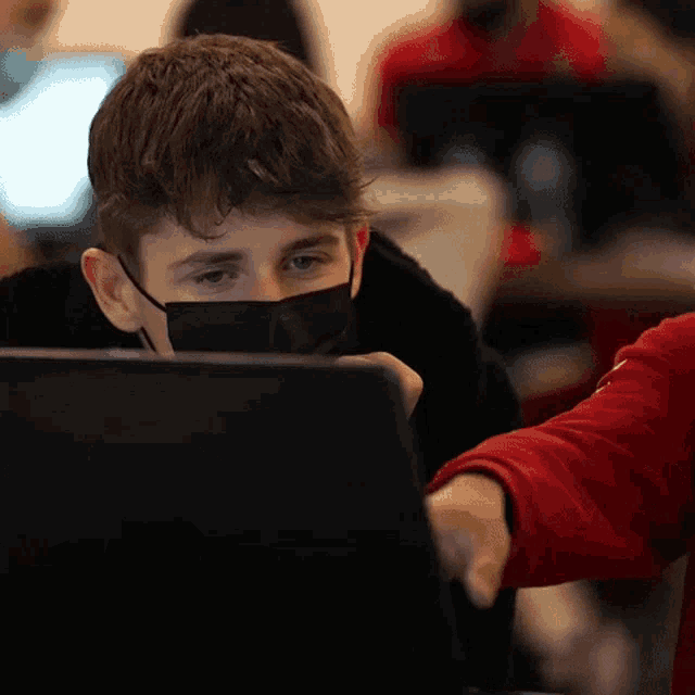 a boy wearing a mask is using a laptop