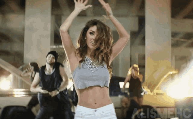 a woman in a crop top and shorts is dancing in front of a sign that says alignment
