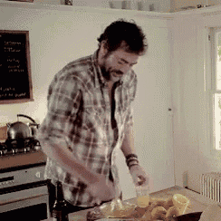 a man in a plaid shirt is standing in a kitchen