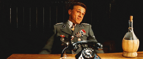 a man in a military uniform is sitting at a table with his arms outstretched