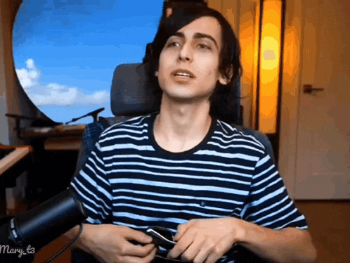 a man wearing a striped shirt is sitting in a chair with mary t3 written on the bottom