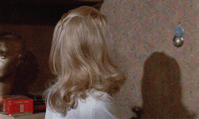 a woman with blonde hair is standing in front of a wall with a can opener on it