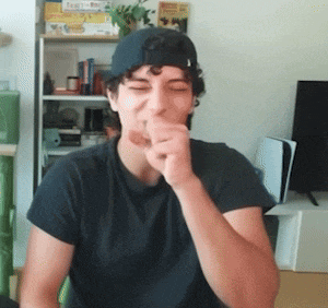 a man wearing a baseball cap and a black shirt is covering his mouth