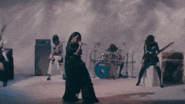 a woman playing a guitar in front of a drum set that says tama on it
