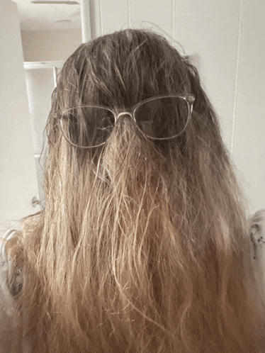 a woman wearing glasses has a ponytail behind her