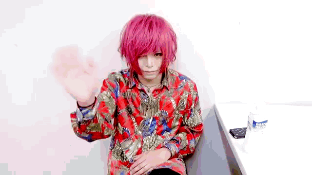a person with red hair and a colorful shirt is sitting in a chair .