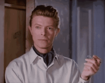 a man in a white shirt and tie is holding a glass in his hand and smoking a cigarette .