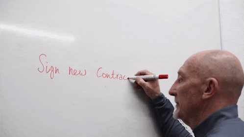 a man is writing on a whiteboard that says " sign new contract "
