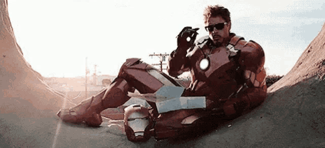 a man in a iron man suit is sitting on top of a concrete wall .