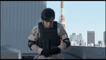 a man in a military uniform is standing on a rooftop with a city in the background ..