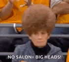 a woman with a big wig on her head is sitting in the stands .