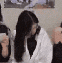 a woman with long hair is sitting at a table with a cell phone in her hand .