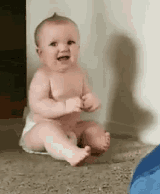 a baby in a diaper is sitting on the floor .