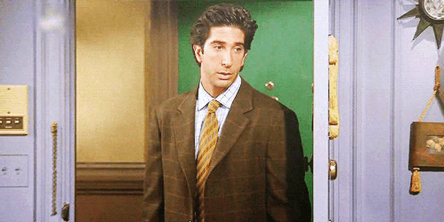 a man in a suit and tie is standing in front of a green door
