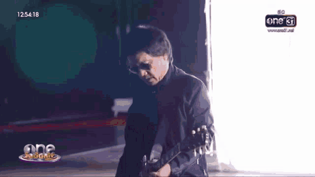 a man is playing a guitar in front of a screen that says one31