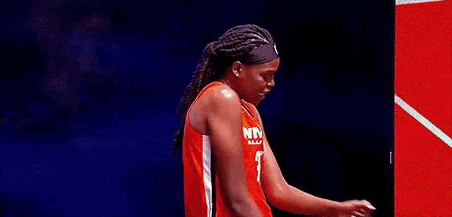 a female basketball player wearing an orange jersey with the number 25 on it