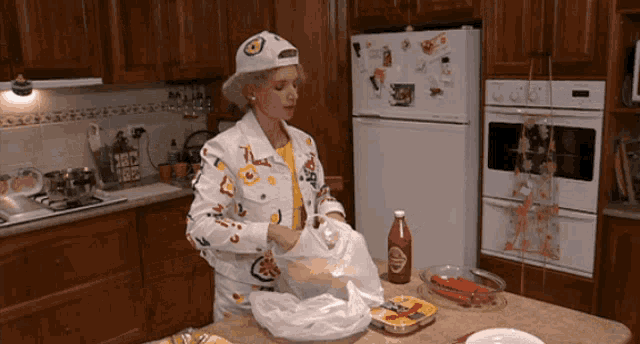 a woman in a kitchen with a bottle of tabasco sauce on the counter
