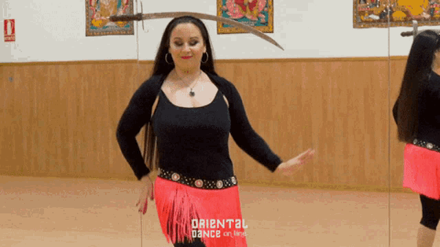 a woman dancing in front of a mirror with oriental dance on the bottom right