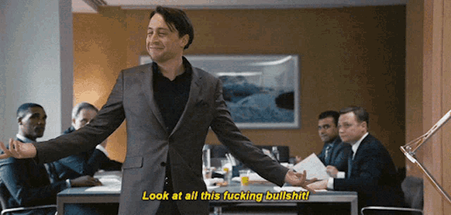 a man in a suit says " look at all this fucking bullshit " in front of a group of people