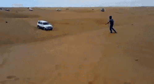 a white suv is flying through the air in the middle of a desert