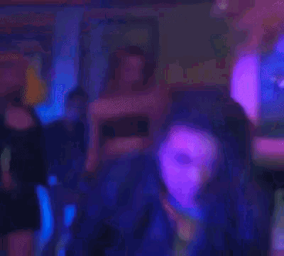 a man is dancing in a dark room with purple lights