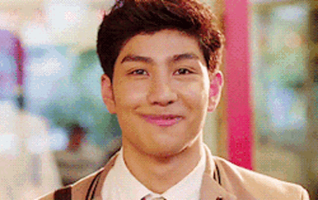 a young man wearing a suit and tie is smiling .