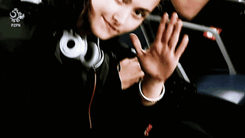 a girl wearing headphones is waving her hand in front of a bag that says pzpn