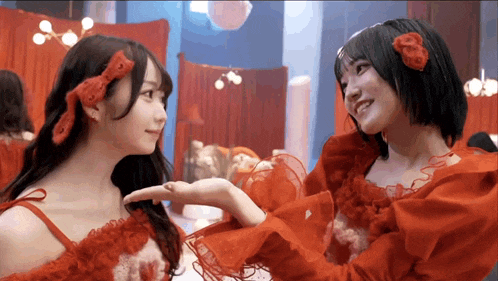 a woman in a red dress holds another woman 's hand