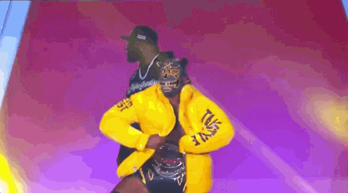 a man in a yellow jacket is dancing on a stage with a tiger mask on his head .