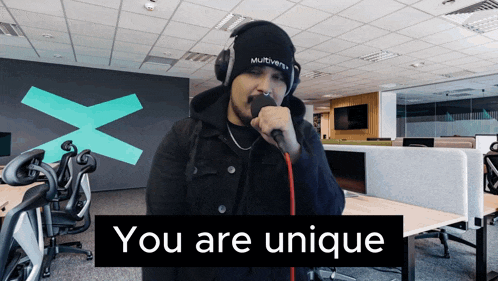 a man singing into a microphone with the words " you are unique " behind him