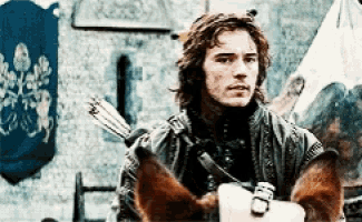 a man with long hair is riding a horse with a sword in his hand .