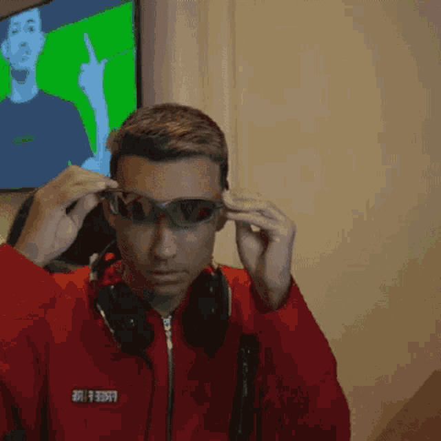 a man wearing sunglasses and headphones has a red jacket with the word free on the front