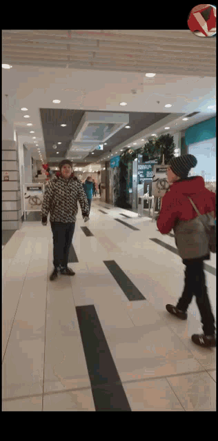 a woman in a red jacket walks down a hallway