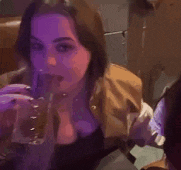 a woman is drinking a drink through a straw in a dark room .