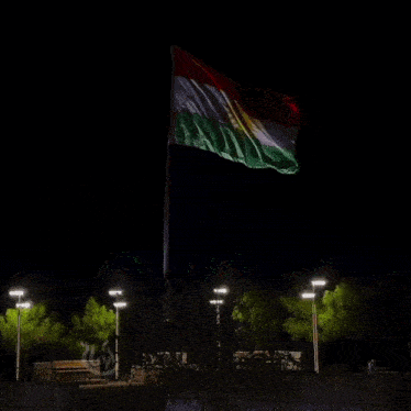 a red white and green flag is flying in the wind at night