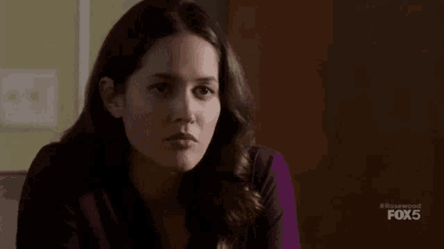 a woman in a purple shirt is sitting on a couch and looking at something .