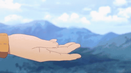 a person 's hand is reaching out towards a mountain range .