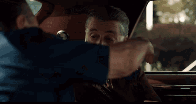 two men hugging in a car with one wearing a watch