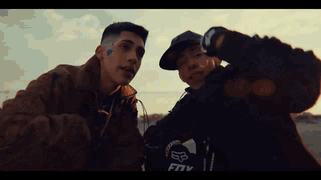 two young men are standing next to each other and one has a tattoo on his face that says fox