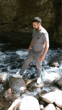 a man standing on a rock near a river with a t-shirt that says ' abercrombie & fitch '