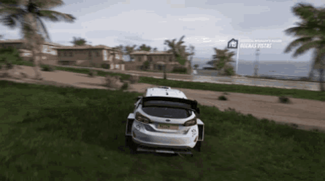 a white car is driving through a grassy field with a sign that says buena vista