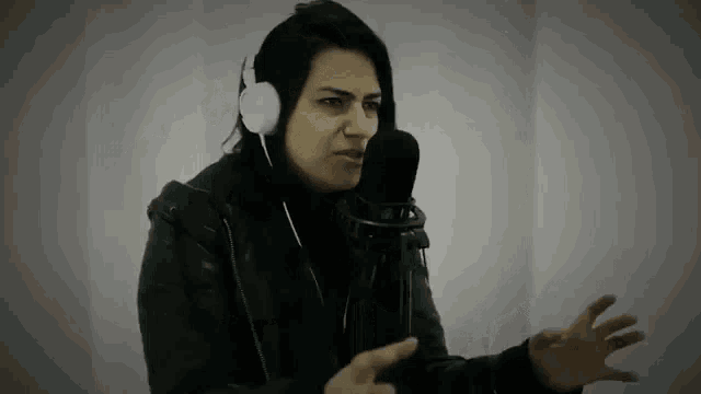 a woman wearing headphones and a leather jacket is talking into a microphone .