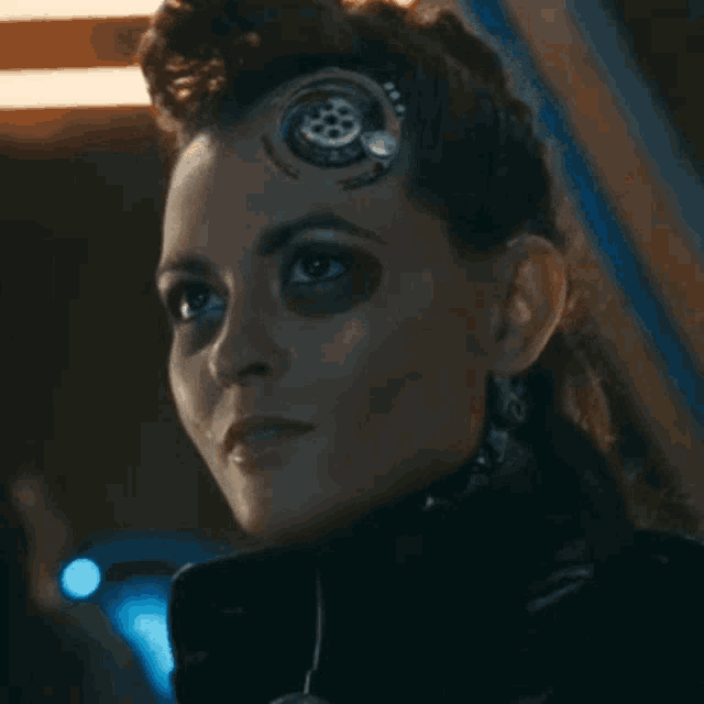 a close up of a woman 's face with a robotic eye on her forehead