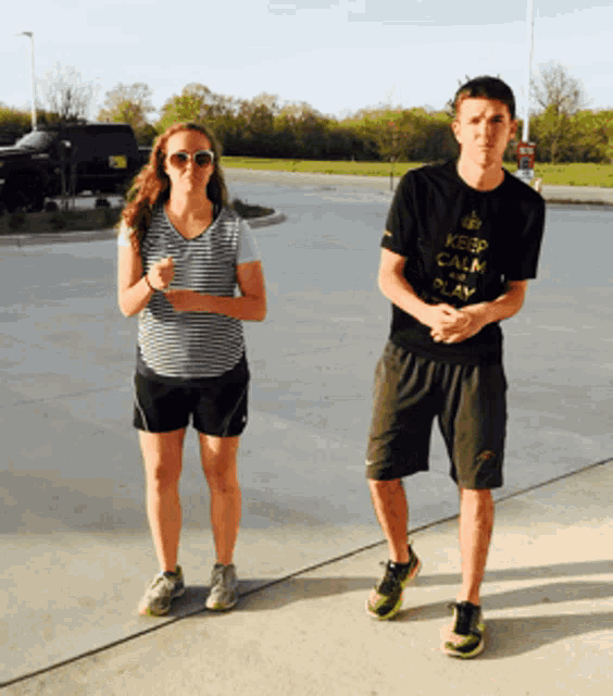 a man wearing a black shirt that says keep calm and play is standing next to a woman