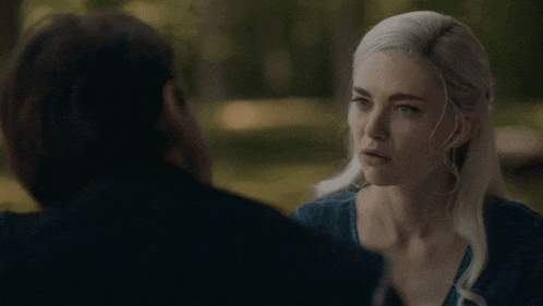 a man and a woman are looking at each other in a dark forest