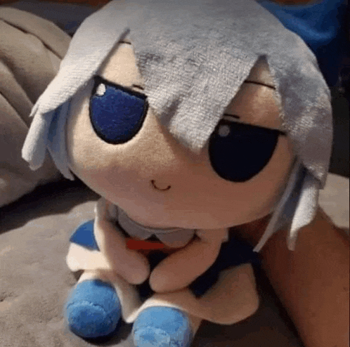 a person is holding a stuffed animal that looks like a girl with blue eyes and white hair .