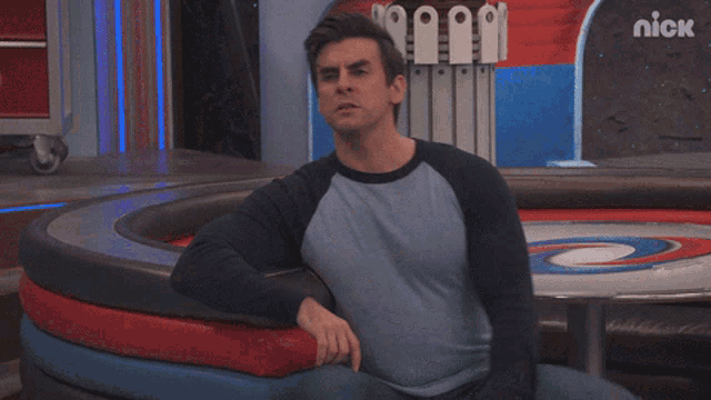 a man is sitting in front of a nick logo