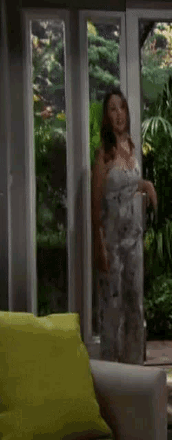 a woman in a white jumpsuit is standing in front of a window