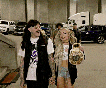 a man and a woman are holding hands and the woman is holding a wwe championship belt